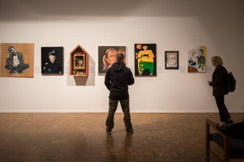 Person standing in front of portraits in an art gallery