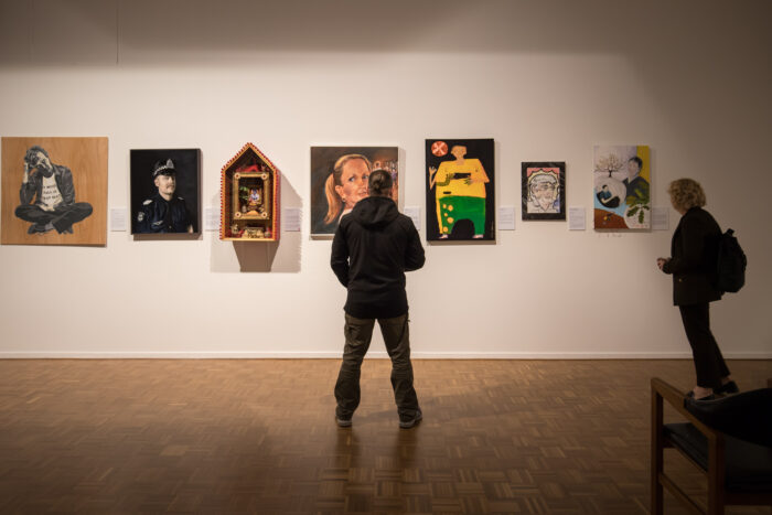 Person standing in front of portraits in an art gallery