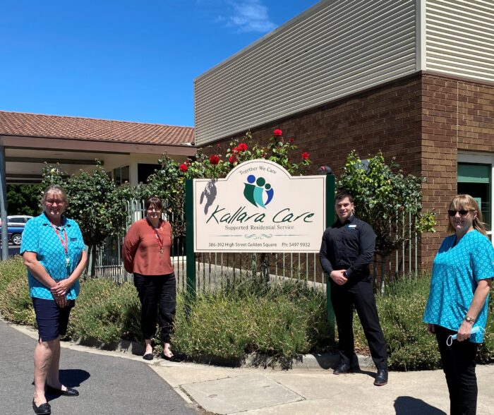 Four people standing in front of the Kallara Care sign which is in a graden at the front of the building