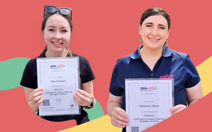 Cassandra Albutt and Shea Donohue smile after graduation against a coral background with green and yellow shapes, each holding their are-able Education and Training Certificate III in Early Childhood Education and Care certificate towards the camera.
